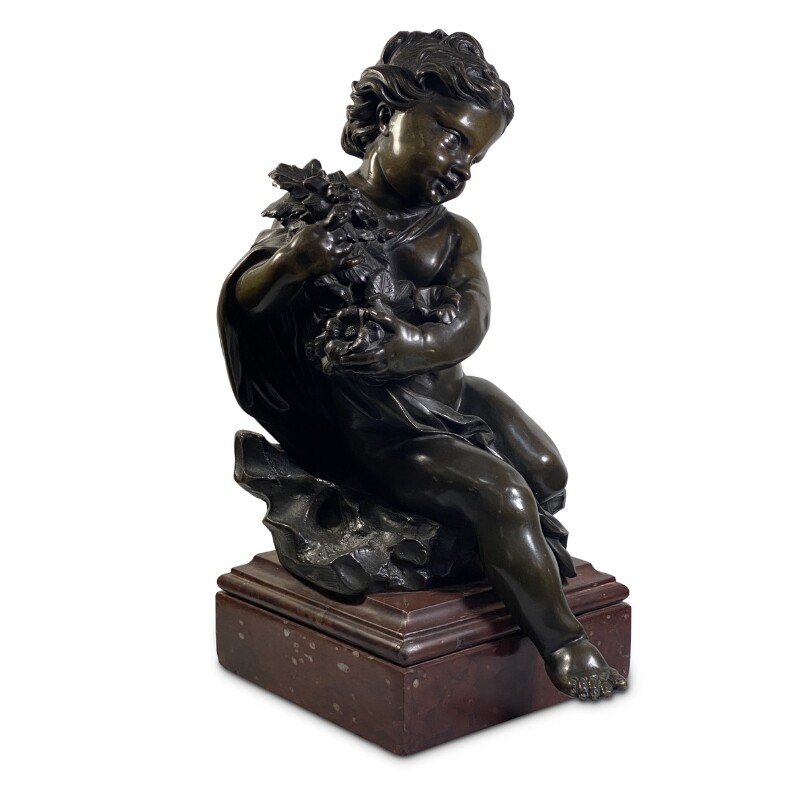 Bronze figure of a child holding a floral arrangement set on a marble base