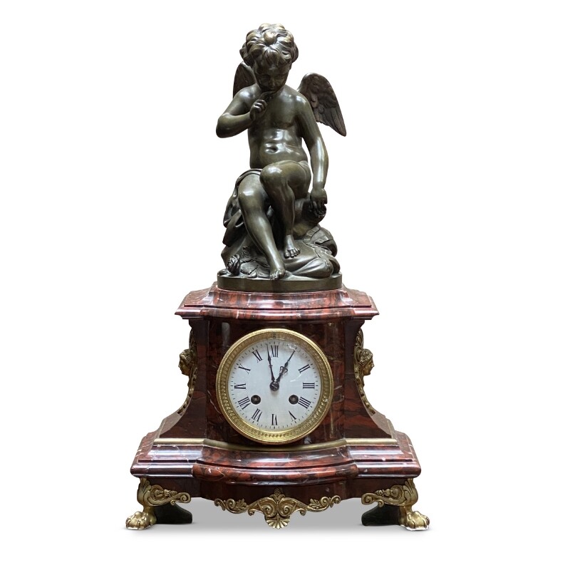 French mantle clock featuring a bronze cupid figure on a rouge marble base